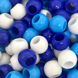 May include: A close-up of a pile of colorful plastic beads. The beads are white, light blue, and dark blue. They are all round and have a hole in the center.