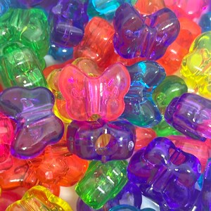 May include: Assortment of colorful plastic butterfly beads. The beads are translucent and have a shiny finish. They are perfect for making jewelry, crafts, and other projects.