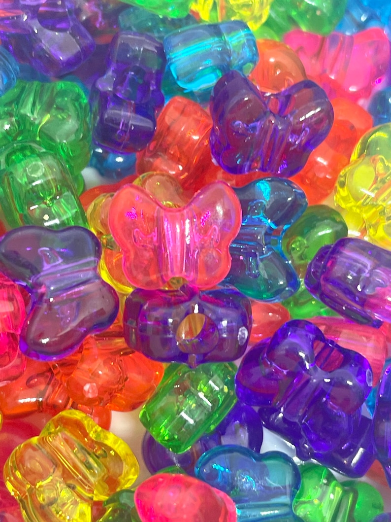 May include: Assortment of colorful plastic butterfly beads. The beads are translucent and have a shiny finish. They are perfect for making jewelry, crafts, and other projects.