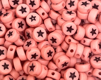 May include: A large pile of pink plastic beads with black star designs. The beads have a hole through the center for stringing.