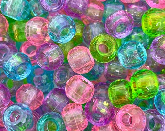May include: A close-up of a pile of colorful, faceted plastic beads. The beads are translucent and have a variety of colors, including pink, blue, green, and purple.