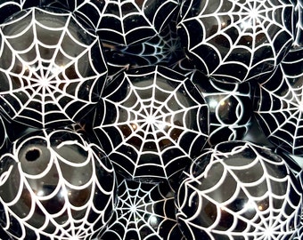 May include: A group of black and white Halloween decorations shaped like spheres with a spiderweb design.
