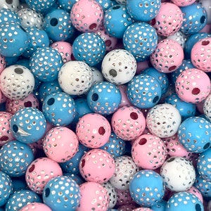 May include: A collection of round, plastic beads with a textured surface. The beads are in shades of blue, pink, and white with silver glitter accents.