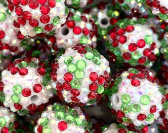 May include: A close-up of a collection of white, red, and green Christmas ornaments. The ornaments are covered in small, sparkly rhinestones.