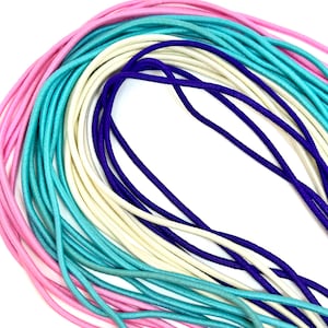 May include: A collection of colorful elastic cord in pink, blue, and white. The cord is arranged in a layered pattern, with the pink cord on the bottom and the white cord on the top.