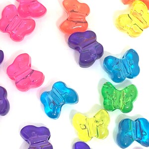 May include: Assortment of colorful plastic butterfly beads. The beads are translucent and come in a variety of colors, including pink, orange, yellow, green, blue, and purple.