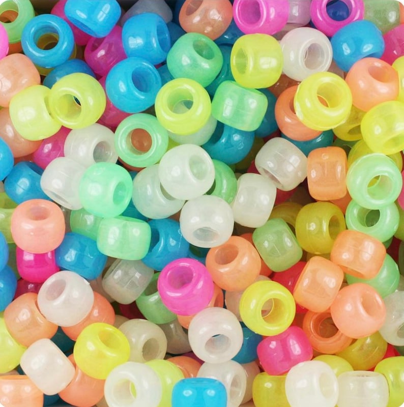 May include: A large assortment of glow-in-the-dark beads in various colors, including pink, blue, green, yellow, and white. The beads are round and have a smooth, glossy finish.