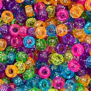May include: A large assortment of colorful, glittery plastic beads. The beads are round with a hole in the center and are perfect for making bracelets, necklaces, and other crafts.