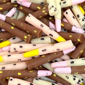 May include: A pile of colorful, patterned, plastic sticks with black spots and yellow, pink, or brown tips.