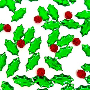 May include: Green holly leaf shaped Christmas ornaments with red berry accents.