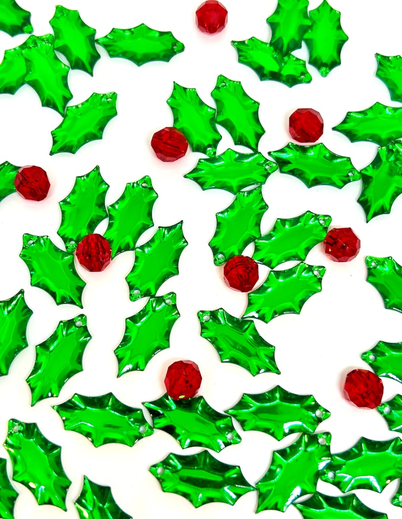 May include: Green holly leaf shaped Christmas ornaments with red berry accents.