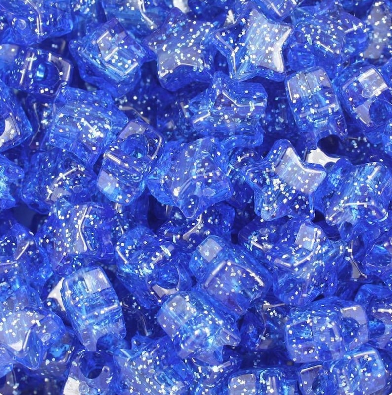 May include: A close-up of a pile of blue star-shaped beads with glitter embedded in the plastic.