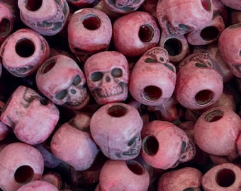 May include: A close-up of a pile of purple skull-shaped beads. The beads are made of plastic and have a matte finish.