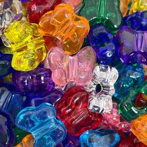 Pu&ograve; includere: Assortimento di perline di plastica a forma di farfalla colorate. Le perline sono trasparenti e disponibili in una variet&agrave; di colori, tra cui rosso, blu, verde, giallo, arancione e viola.