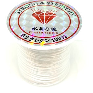 Pu&ograve; includere: Filo elastico bianco su una bobina con un'etichetta olografica che recita "Strong & Stretchy" e "Elastricstring 100%".