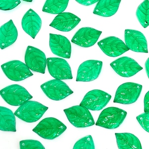 Peut inclure: Une collection de feuilles en verre vert avec un trou en haut. Les feuilles sont translucides et ont une surface légèrement texturée.