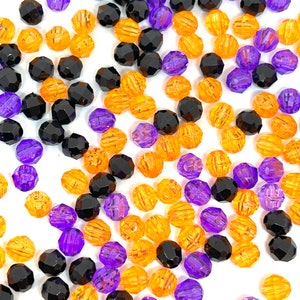 May include: A collection of black, orange, and purple beads. The beads are faceted and have a ribbed texture.