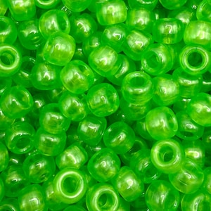 May include: A large collection of small, round, translucent neon green pony beads. Each bead features a smooth, glossy finish and a central hole for threading. The beads are piled together, creating a vibrant, uniform display of bright green color.