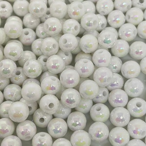 May include: A large pile of white iridescent round beads. The beads have a hole in the center for stringing.