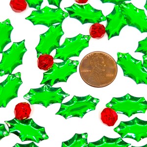 May include: A scattering of green holly leaves with red berry accents. The leaves are shiny and have a slightly iridescent finish. The berries are small and round.