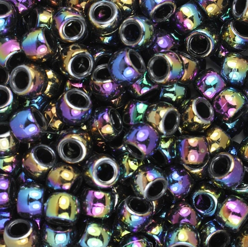 May include: A large pile of iridescent black round beads. The beads have a metallic sheen and reflect different colors of the rainbow.
