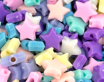 May include: A collection of pastel-colored plastic star-shaped beads. The beads are in shades of pink, purple, blue, yellow, and green.
