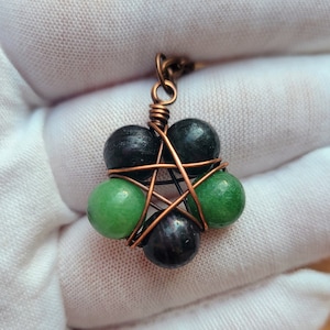 May include: A copper wire wrapped pendant with green and black beads in the shape of a five-pointed star.