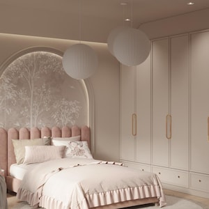 Op de afbeelding: Een roze gestoffeerd bed met een geruit beddengoed en een wit hoofdeinde. Het bed staat in een slaapkamer met witte muren en een wit plafond. Er hangen drie witte bolvormige hanglampen aan het plafond. Er zijn ook witte kastdeuren met gouden handgrepen.