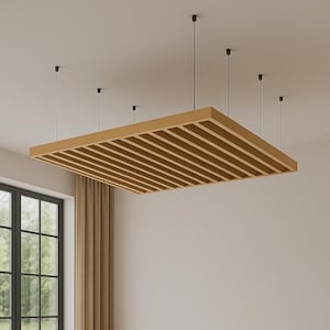 May include: A rectangular wooden ceiling panel with a slatted design, suspended from the ceiling by black cords. The panel is a light brown color and appears to be made of wood. The room has a window and neutral-colored curtains.