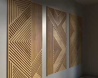 Op de afbeelding: Drie houten wandpanelen met geometrische ontwerpen. Elk paneel heeft een reeks parallelle lijnen en schuine sneden, waardoor een gelaagd effect ontstaat. De panelen zijn gemonteerd op een grijze muur, met een bank zichtbaar in de hoek.
