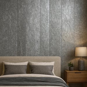 May include: A bedroom scene featuring a bed with neutral-toned bedding and pillows. The headboard is beige, and the wall behind the bed is covered in vertical gray stone panels. A wooden nightstand with a lamp and a small plant sits beside the bed.