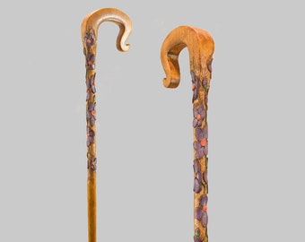 Puede incluir: Dos bastones de madera con un diseño floral tallado. Los bastones son marrones con flores moradas y naranjas.