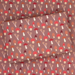 May include: Brown wrapping paper with a repeating pattern of red and orange mushrooms. The mushrooms are of various sizes and shapes, and some have white spots.