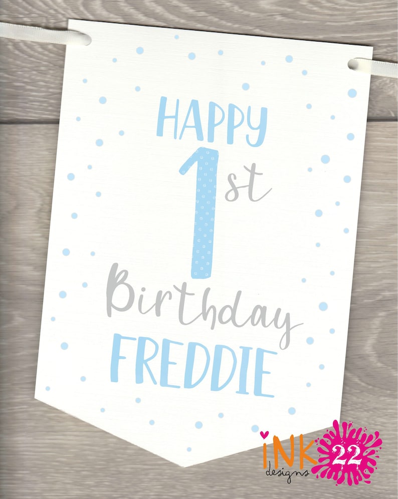 May include: White banner with blue polka dots and the text "Happy 1st Birthday Freddie" in blue and gray lettering.