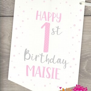 May include: A white banner with pink polka dots and the text "Happy 1st Birthday Maisie". The number 1 is pink with white polka dots.
