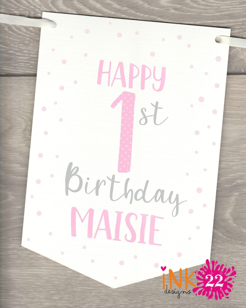 May include: A white banner with pink polka dots and the text "Happy 1st Birthday Maisie". The number 1 is pink with white polka dots.