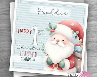 Può includere: Un biglietto a strisce blu e bianche con il testo "Buon 1° Natale a un nipote speciale" e il nome "Freddie". Un Babbo Natale dei cartoni animati è illustrato sulla carta.