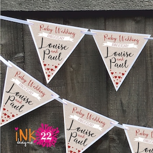 May include: A banner with five triangular flags, each with the text "Ruby Wedding Anniversary" and the names "Louise and Paul". The flags are decorated with red hearts and are strung together with white ribbon.