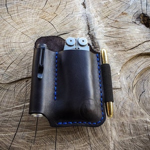 May include: A black leather pocket organizer with blue stitching, holding a multi-tool and a pen.