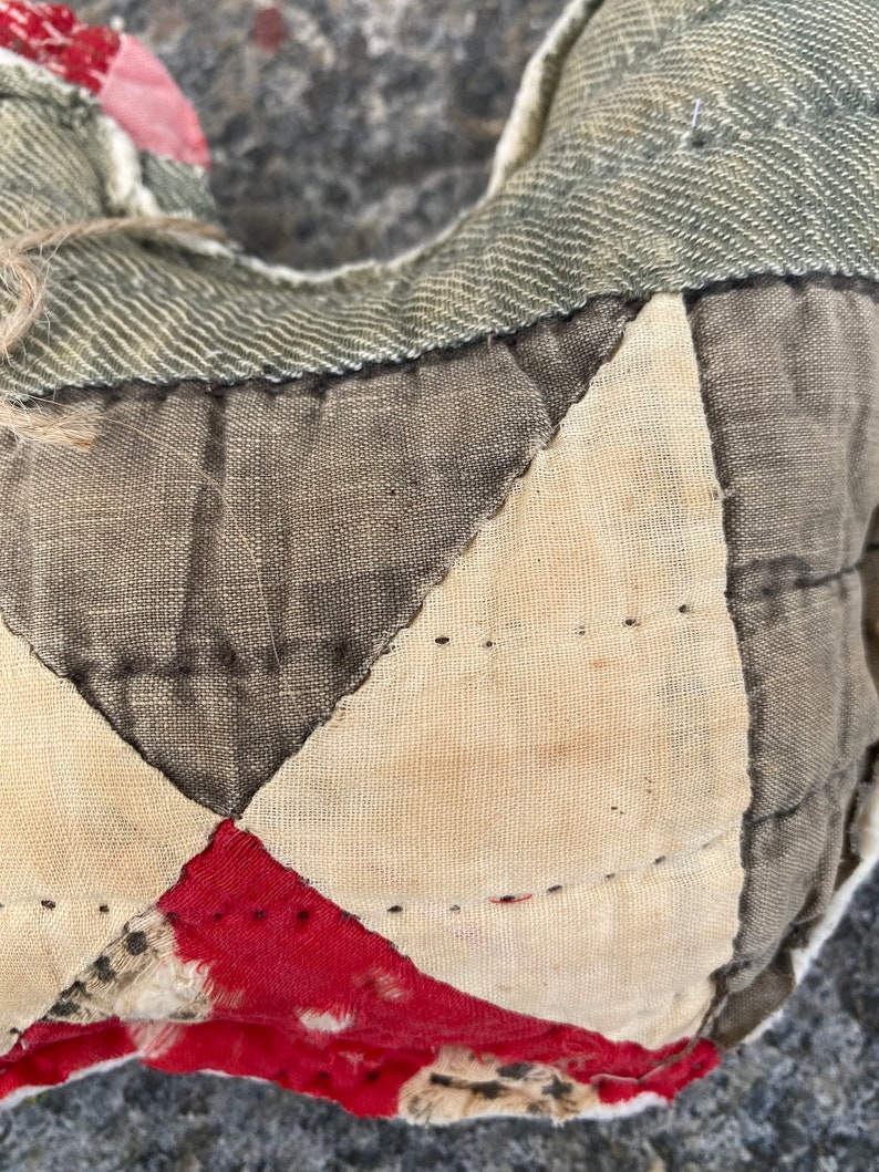 May include: Close-up of a patchwork quilt made from different fabrics in shades of brown, white, and red. The quilt is stitched together with a running stitch.