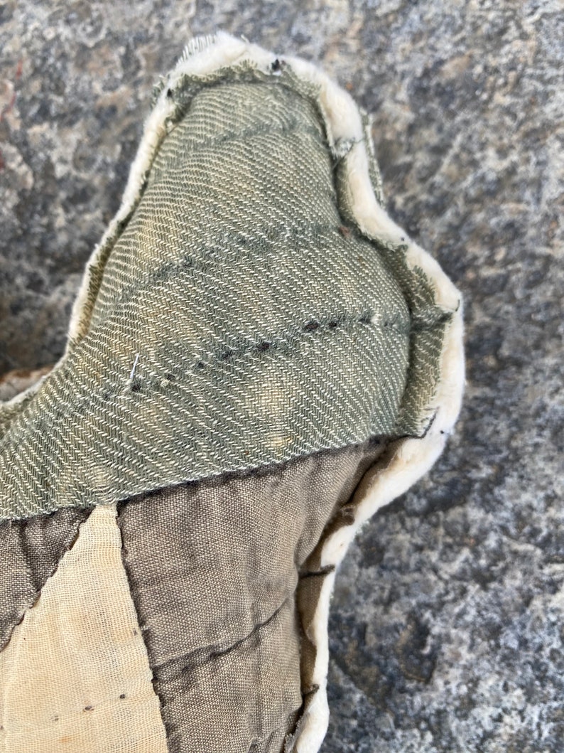 May include: Close-up of a handmade patchwork pillow with a green fabric panel and a white, fluffy trim. The pillow is made of different fabrics and has a quilted design.