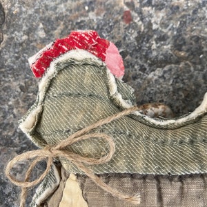 May include: A handmade fabric doll with a green denim bodice, a brown twine bow, and a red and white patchwork fabric head.