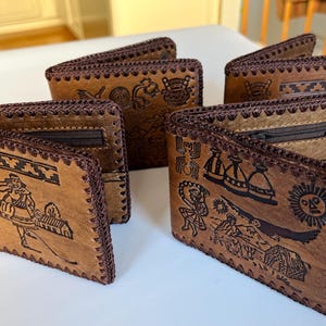 Könnte beinhalten: Fünf braune Ledergeldbörsen mit aufwendigen Designs und braunen Nähten. Die Geldbörsen haben unterschiedliche Designs, darunter geometrische Muster und Figuren.