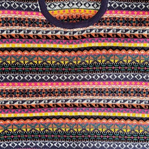 K&ouml;nnte beinhalten: Nahaufnahme eines farbenfrohen Pullovers mit geometrischem Muster. Der Pullover hat horizontale Streifen in verschiedenen Farben, darunter Pink, Gelb, Orange, T&uuml;rkis und Marineblau. Das Design umfasst Diamant- und Zickzackmuster.
