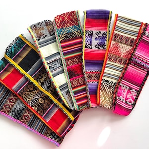 Peut inclure: Une collection de bandes textiles tissées colorées avec des motifs complexes. Les bandes présentent une variété de couleurs, dont le rouge, le rose, le violet et le vert, avec des motifs géométriques et traditionnels. Les bords sont finis avec des coutures décoratives.