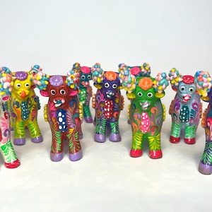 May include: A set of ten colorful ceramic figurines of stylized bulls with horns, each painted with intricate floral patterns in various colors, including white, yellow, red, green, blue, and purple.