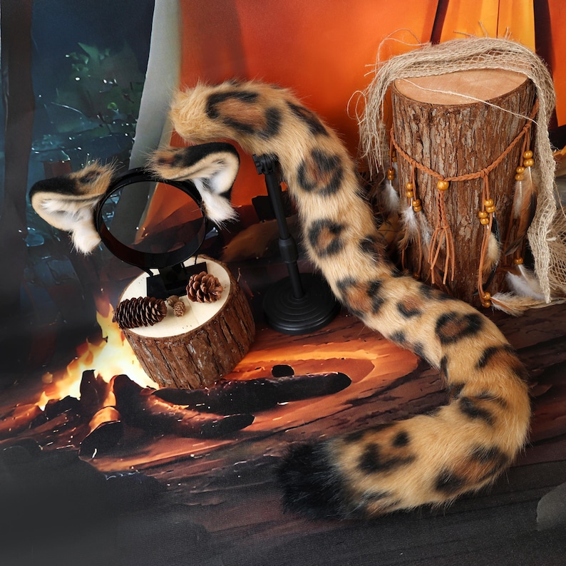 Puede incluir: Una cola de animal de piel sint&eacute;tica y una diadema a juego con orejas, con un color base tostado y manchas de estampado de leopardo en marr&oacute;n oscuro y negro. La cola es larga y curva, terminando en una punta de color negro s&oacute;lido.