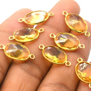 Puede incluir: Ocho conectores de piedras preciosas ovalados de color dorado con bordes facetados. Las piedras preciosas son de color amarillo claro.