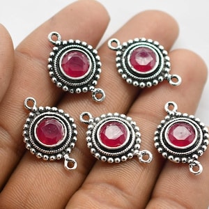 May include: Five silver-toned pendant connectors with a round, red gemstone in the center. Each connector has two loops for attaching to jewelry.