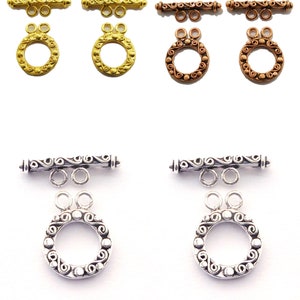 May include: Four sets of ornate toggle clasps for jewelry making. Each set includes a bar with two loops and a round ring with a decorative design. The clasps are available in gold, copper, and silver tones.